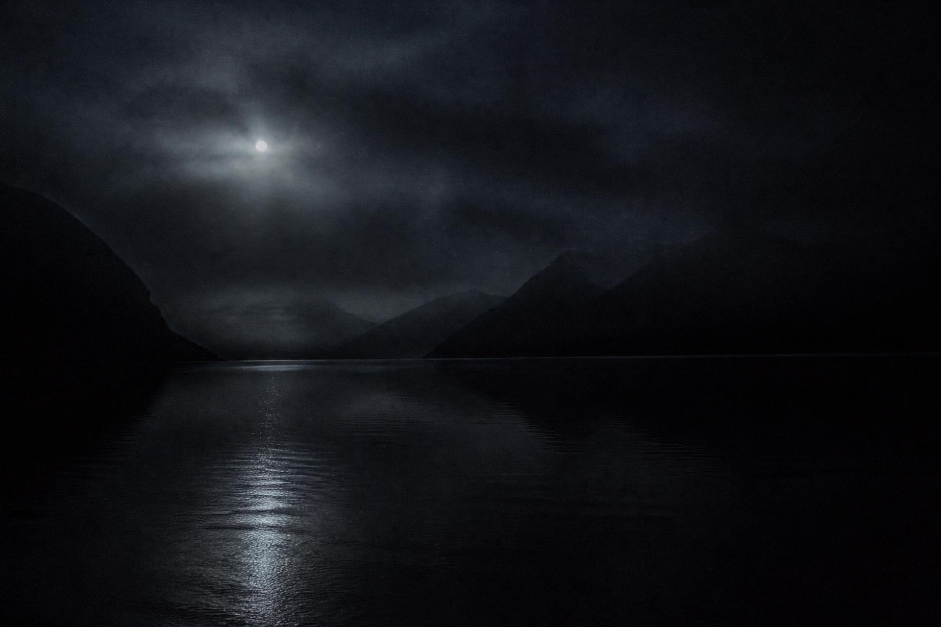 Still black water beneath moonlight and mist